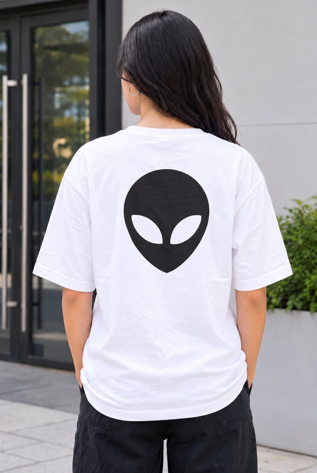 Woman in a white oversized t-shirt with a big black alien head printed on the back